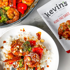 Kevin's Natural Foods honey garlic simmer sauce bottle pour offers sweet-savory glaze for chicken or veggies.