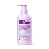 Love Wellness pH Balancing Cleanser bottle on bathroom shelf, fragrance-free and gentle for sensitive skin.