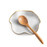 Miamolo spoon rest on stove top with ruffled beige edge, catches drips.