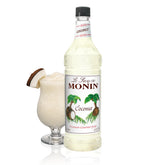 Monin Coconut Syrup bottle pouring into a tropical cocktail for island flavor.