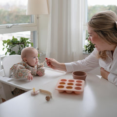 Mushie long sleeve bib wide pocket captures crumbs and drips, protecting outfits.