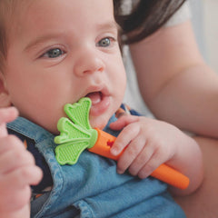 Baby holding the Nuby carrot teether for easy grip by tiny hands