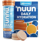 Nuun Immunity bottle poured into a glass of water with blueberry-tangerine flavor.