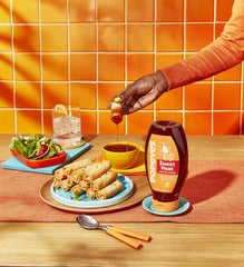 Popeyes Sweet Heat sauce bottle being poured onto a meal for a flavor boost
