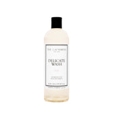 The Laundress Delicate Wash bottle pour demonstrates gentle, controlled dosing for delicate fabrics.