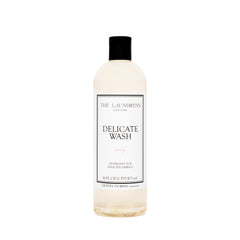 The Laundress Delicate Wash bottle pour demonstrates gentle, controlled dosing for delicate fabrics.