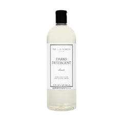 The Laundress Darks Detergent bottle pour showing stain-fighting care for vibrant darks
