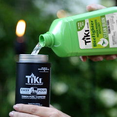 TIKI Clean Burn fuel in use with outdoor torch at twilight, creating a warm glow.
