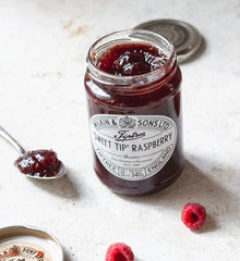 Tiptree Raspberry Preserve with Brie on a cheese board, a refined pairing.