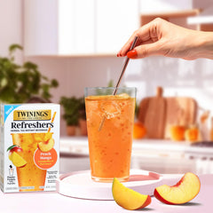 Twinings Peach Mango Refreshers served in a glass with a straw for easy sipping.