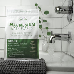 Village Naturals Therapy Muscle Magnesium Bath Flakes closeup in a jar highlighting natural minerals.