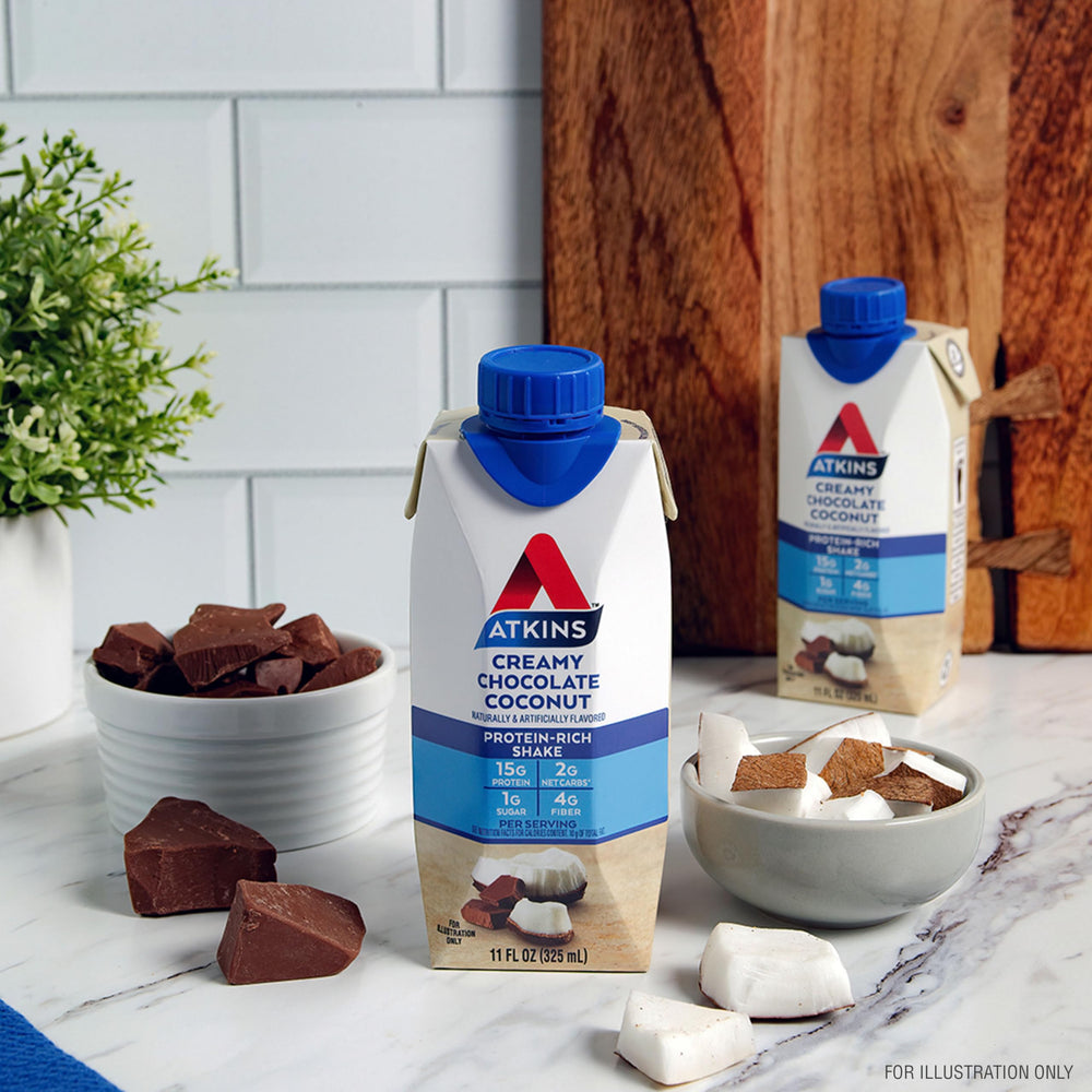 Atkins Creamy Chocolate Coconut Shake label close-up underlines fiber and low net carb content.
