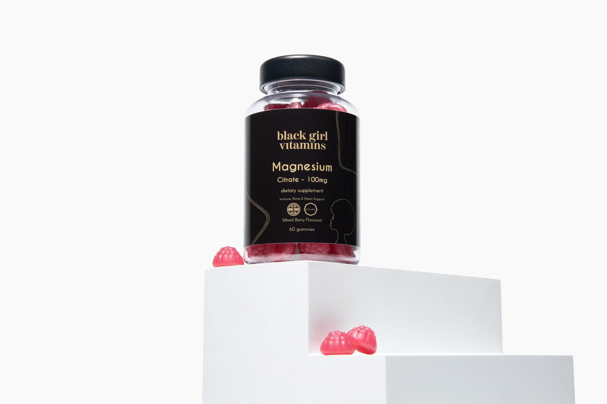 Black Girl Vitamins magnesium gummies beside a glass of water, easy to swallow.