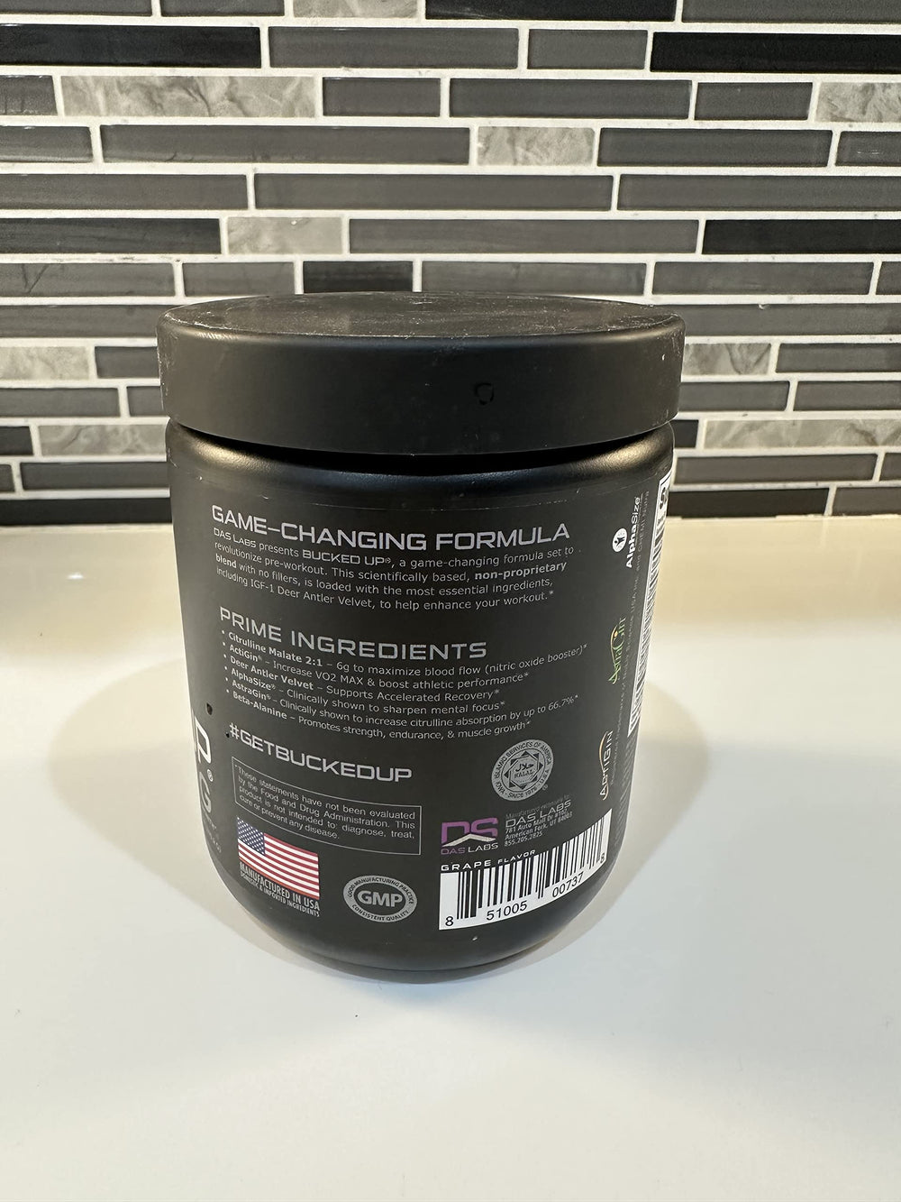Bucked Up Pre Workout grape scoop beside the tub ready to measure.