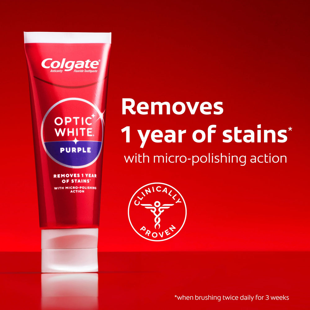 Colgate Optic White Purple toothpaste on countertop beside glass.