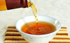 Da Xing Shaoxing wine bottle beside a wok, ideal for authentic Chinese cuisine.