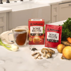 Dr. Kellyann bone broth packets with glass-cup serving for comforting wellness rituals.