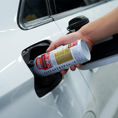 Gumout Multi-System Tune-Up bottle being poured into fuel tank for cleaner system.