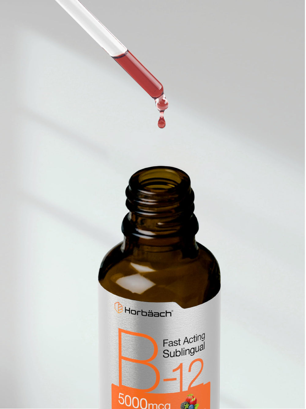 Berry-flavored Horbaach B12 drops alongside glass of water for intake.