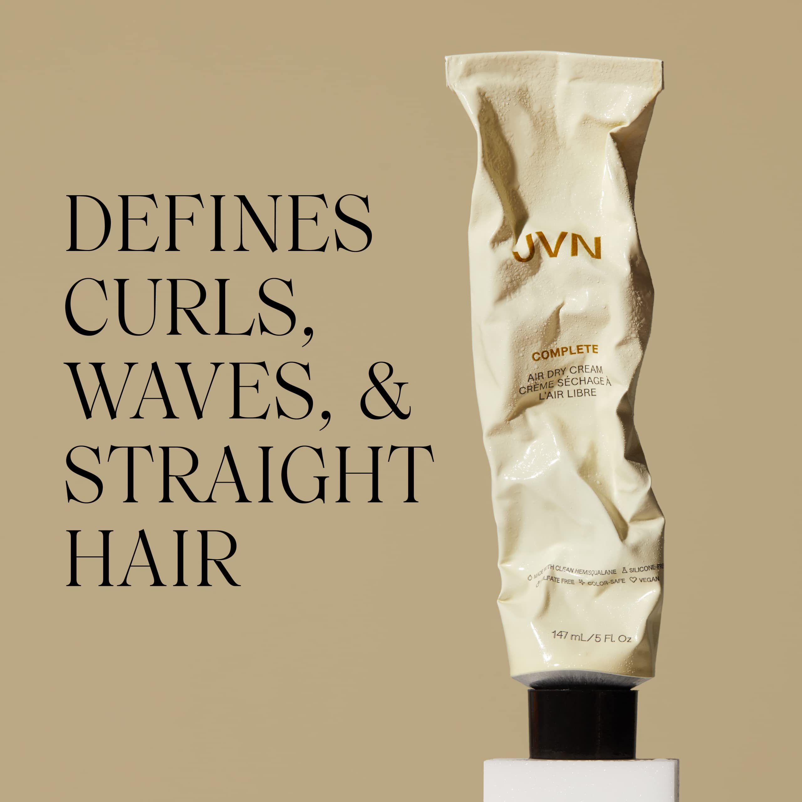 Applying JVN No Heat Cream to damp hair for even distribution.