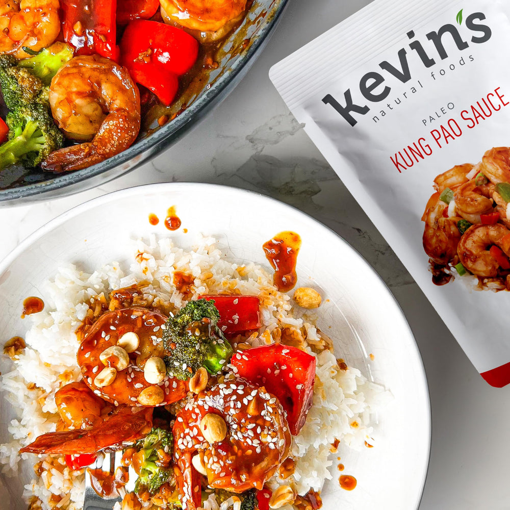 Kevin's Natural Foods honey garlic simmer sauce bottle pour offers sweet-savory glaze for chicken or veggies.