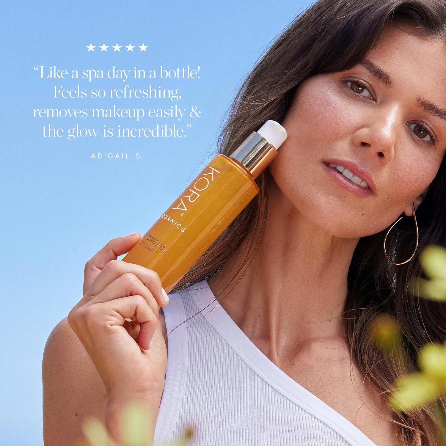 KORA Organics hand application shows cleanser spreading on face and neck.