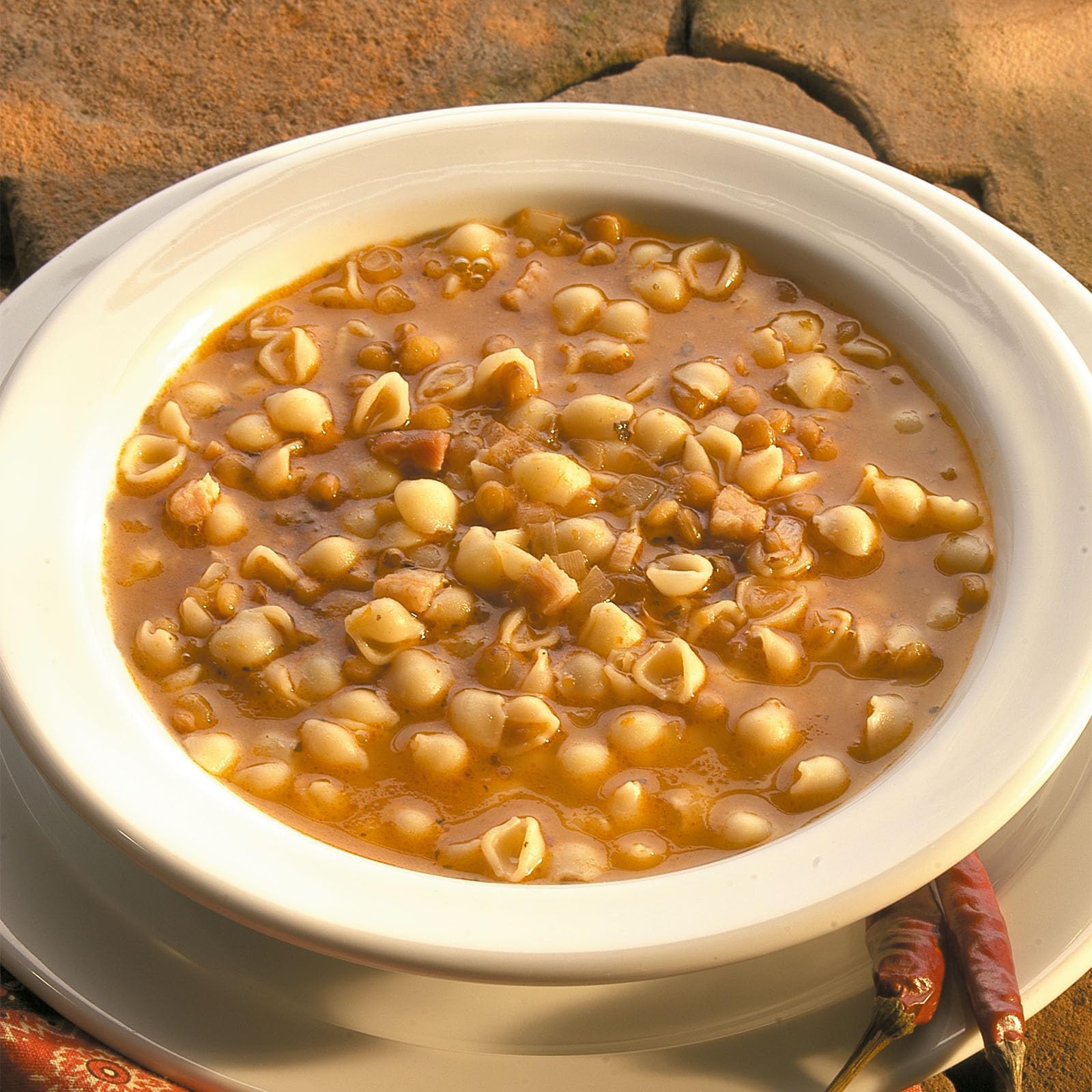 Serving bowl with shells and vegetables, vibrant family meal.