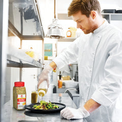 Pouring Lawry's Salt-Free 17 Seasoning over a plated seafood dish