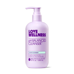 Love Wellness pH Balancing Cleanser bottle on bathroom shelf, fragrance-free and gentle for sensitive skin.