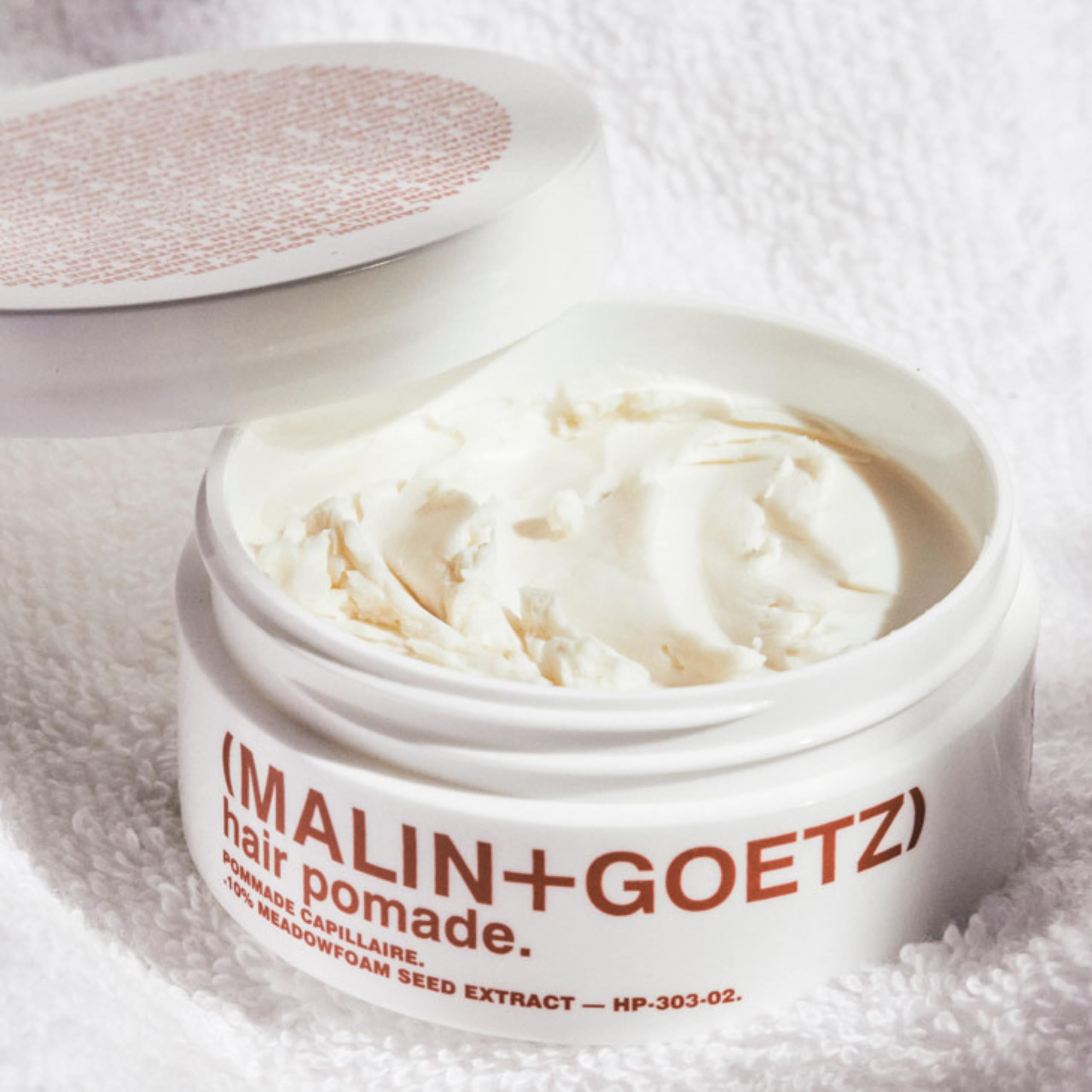 MALIN+GOETZ Hair Pomade jar closeup highlights rich oils and smooth finish.