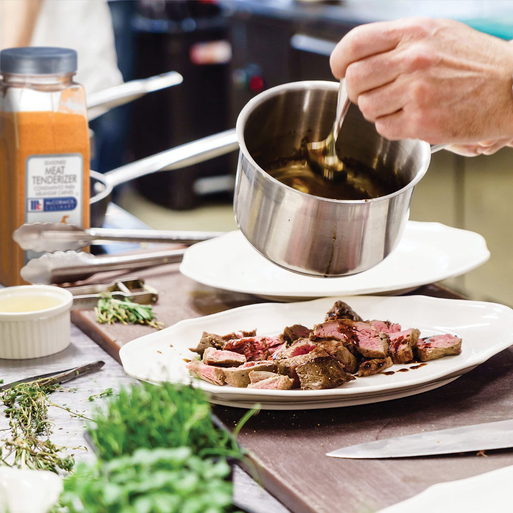 Applying McCormick Culinary tenderizer to meat before cooking.