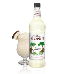 Monin Coconut Syrup bottle pouring into a tropical cocktail for island flavor.
