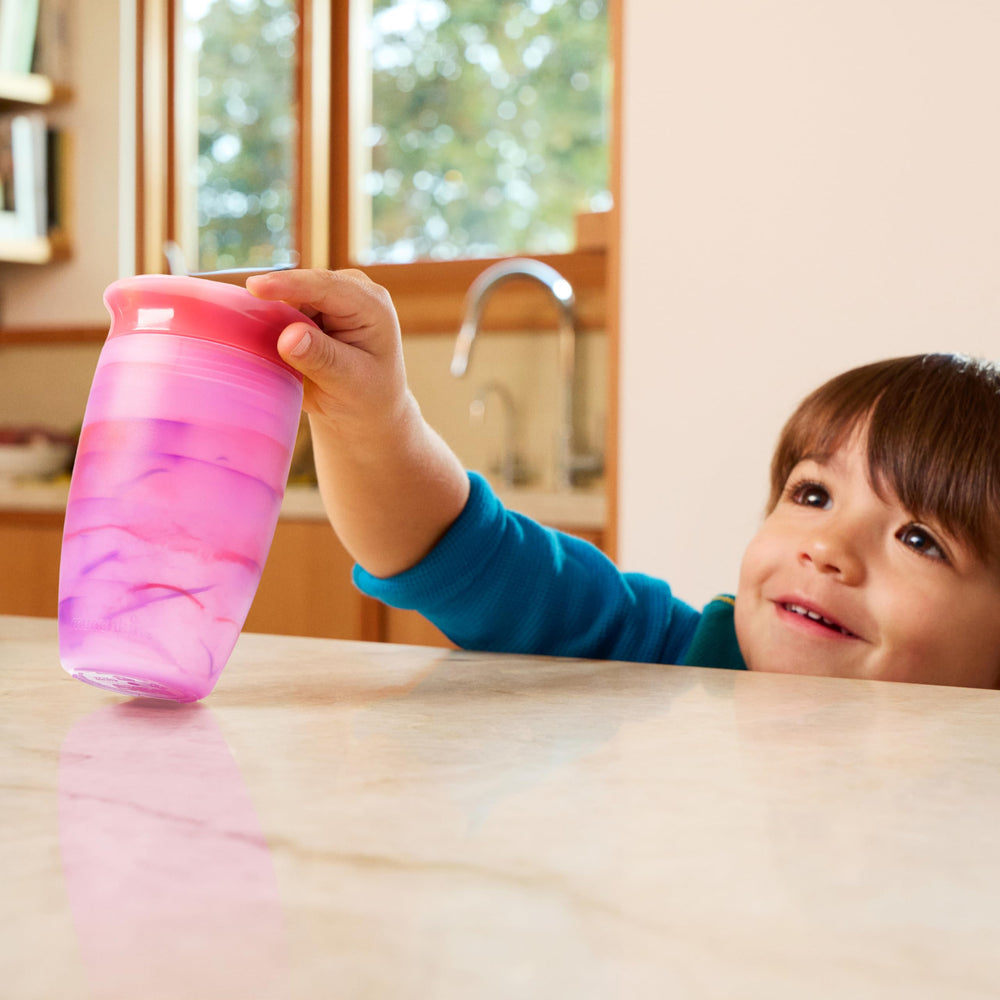 Munchkin Miracle 360 Tropical Swirl cup shown being used by a toddler on the go.