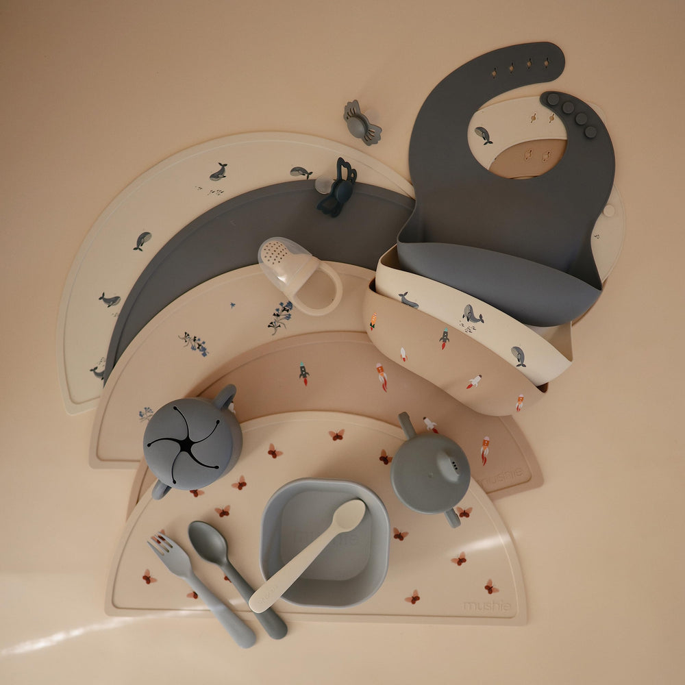 Mushie silicone bib with built-in neck fasteners for a snug, adjustable wear.
