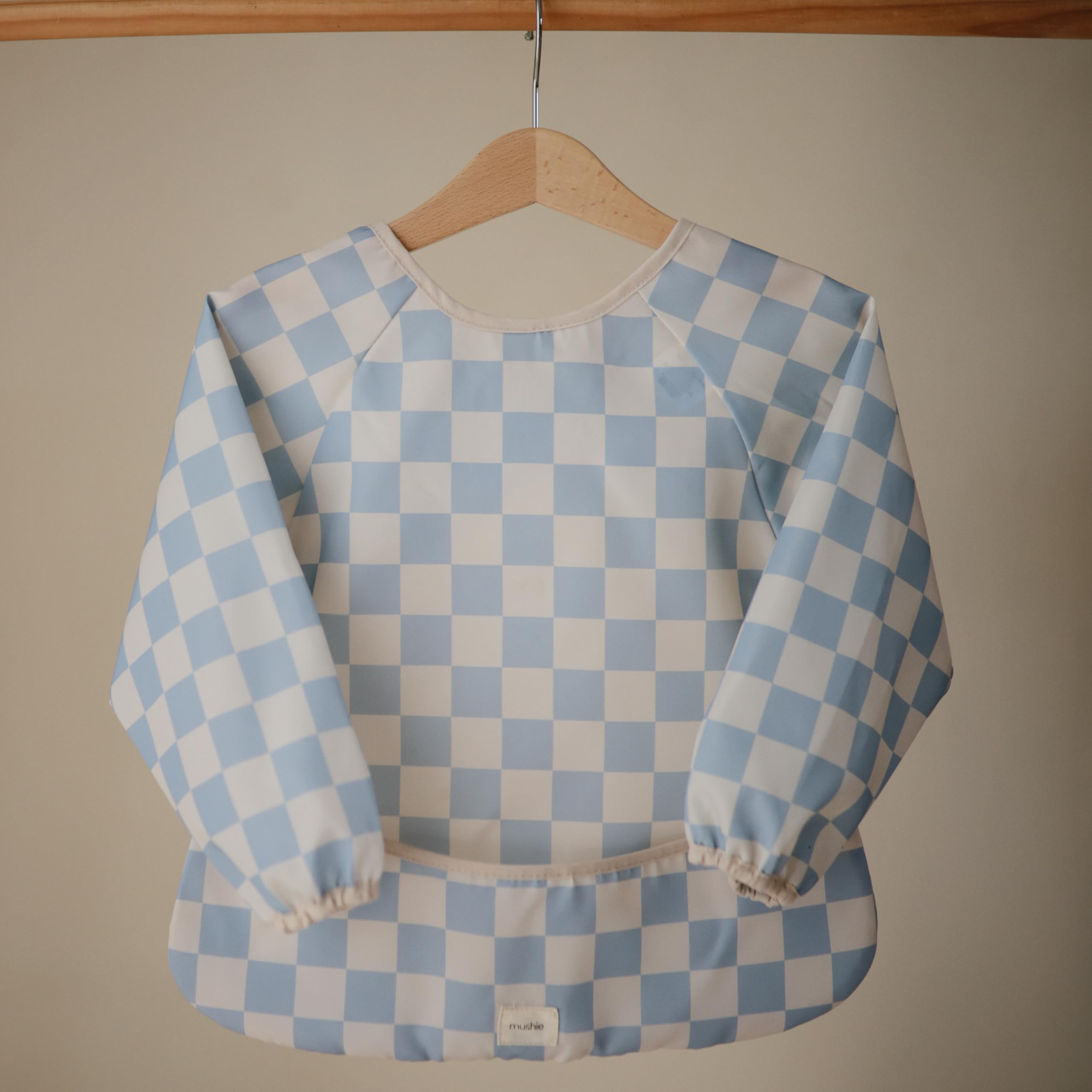 Mushie blue check bib pocket catches crumbs during mealtime.