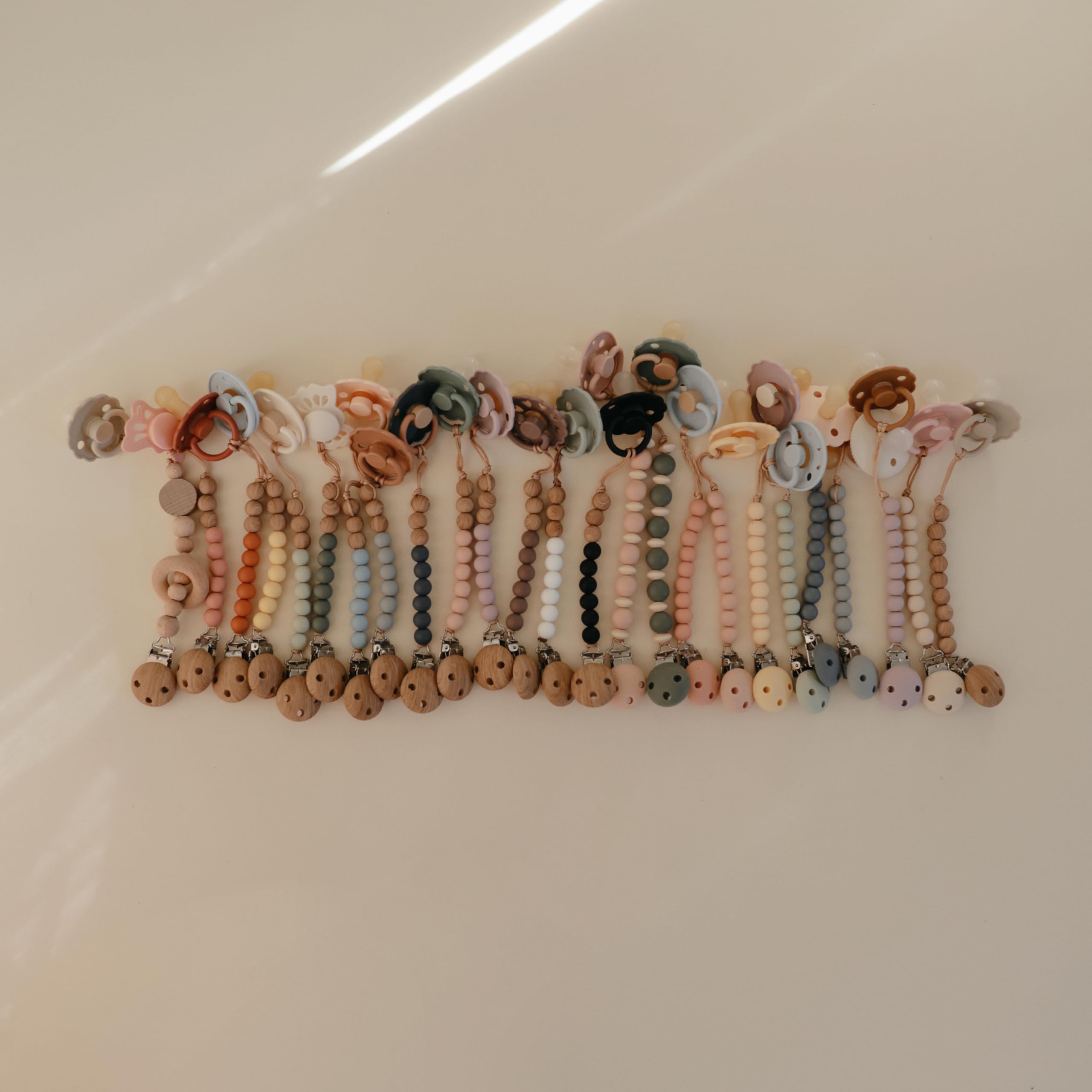 Mushie Hera pacifier clip care instruction image highlights easy hand-wash cleaning.