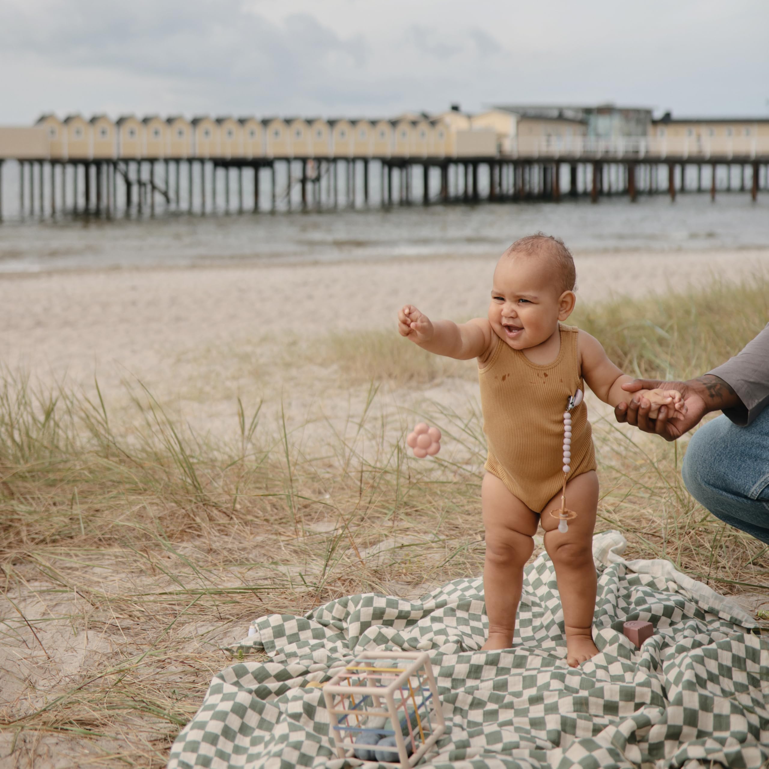 Mushie Hera pacifier clip shown on a baby to prevent dropped pacifiers.