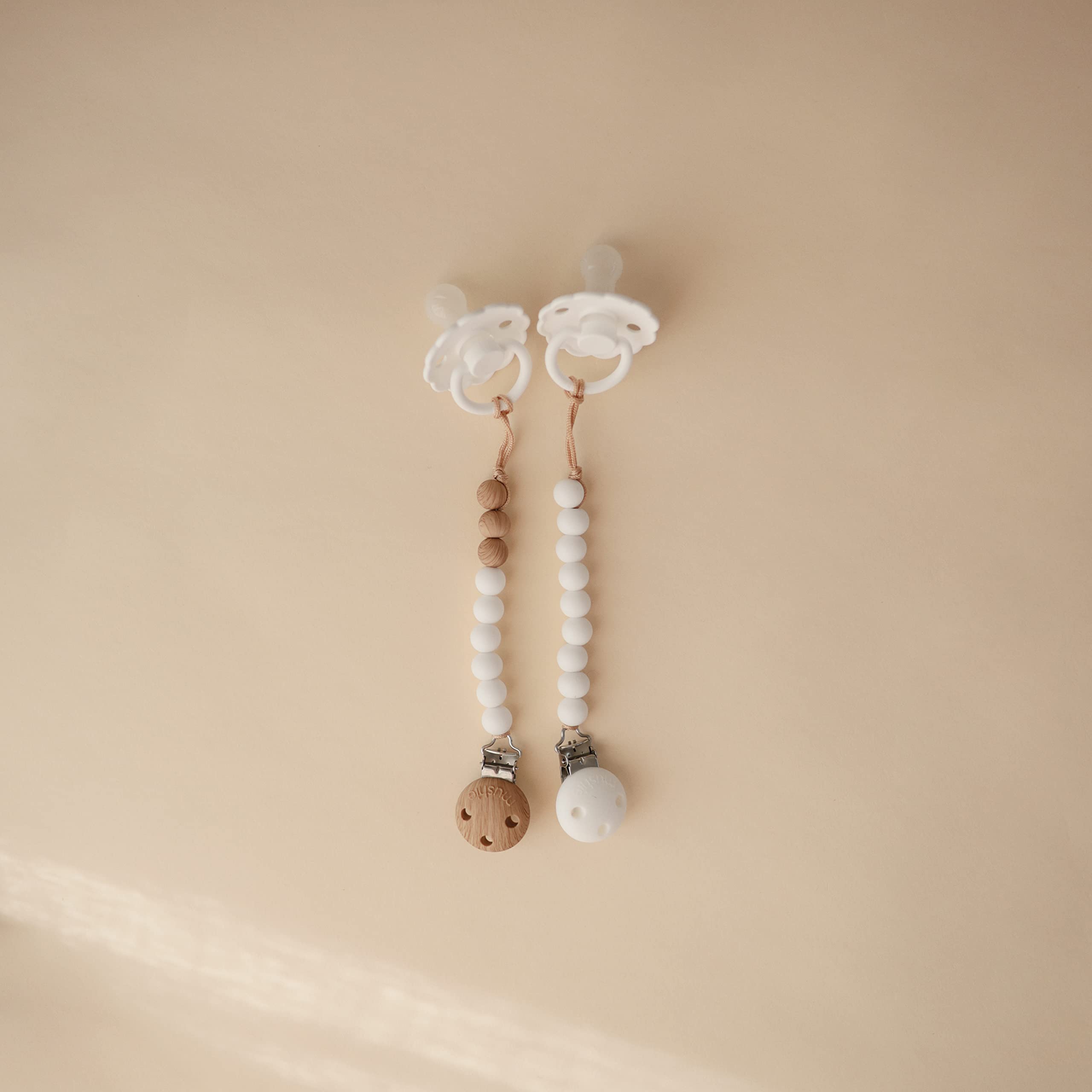 Mushie Hera pacifier clip close-up shows screw-free silicone clasp for safer use.