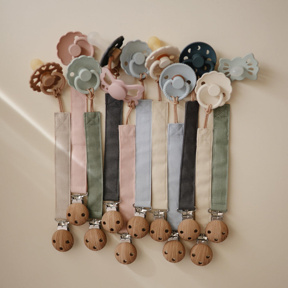 Mushie linen pacifier clip cream close-up, soft fabric strap for baby's comfort