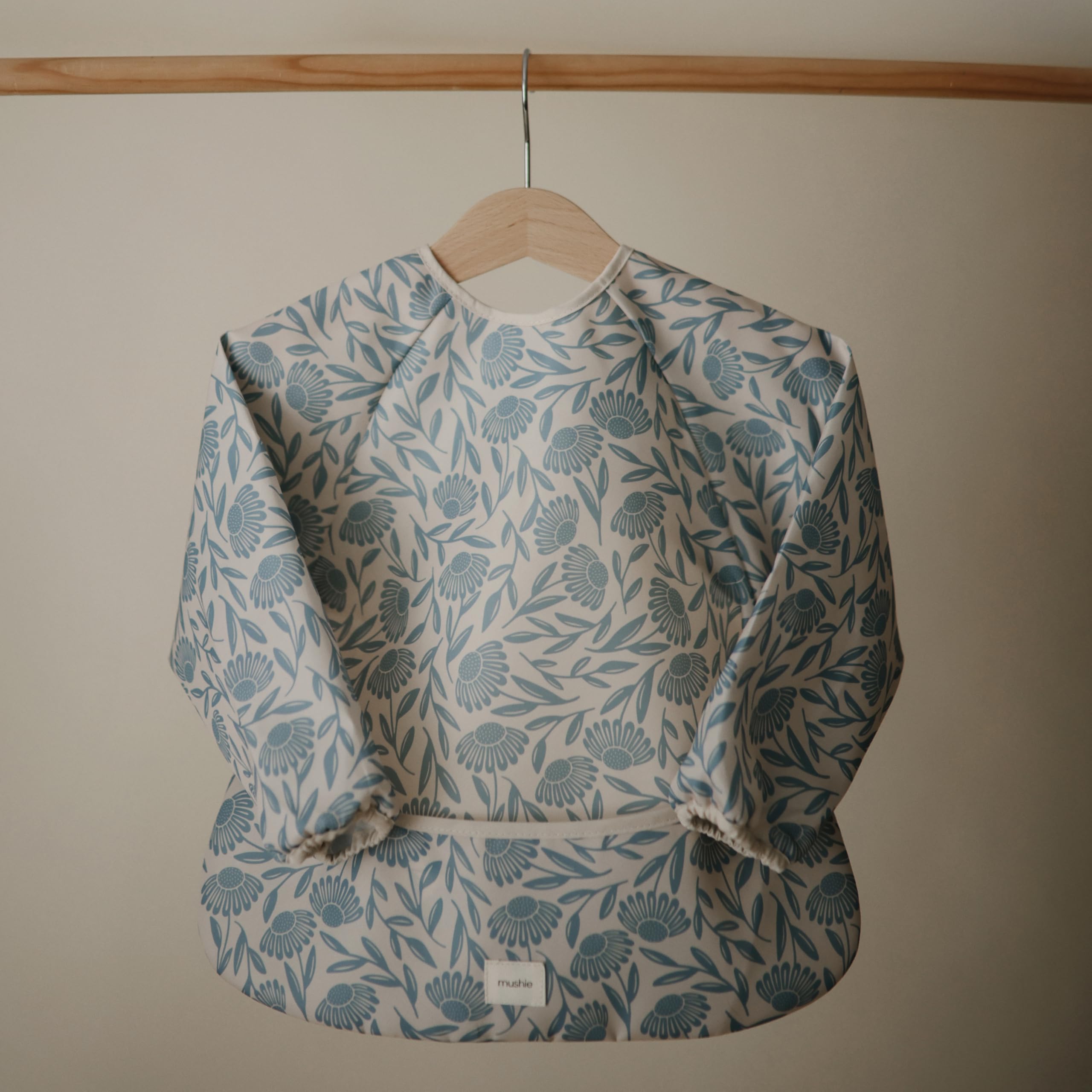 Mushie long sleeve bib blue flowers fabric closeup highlights water-resistant material