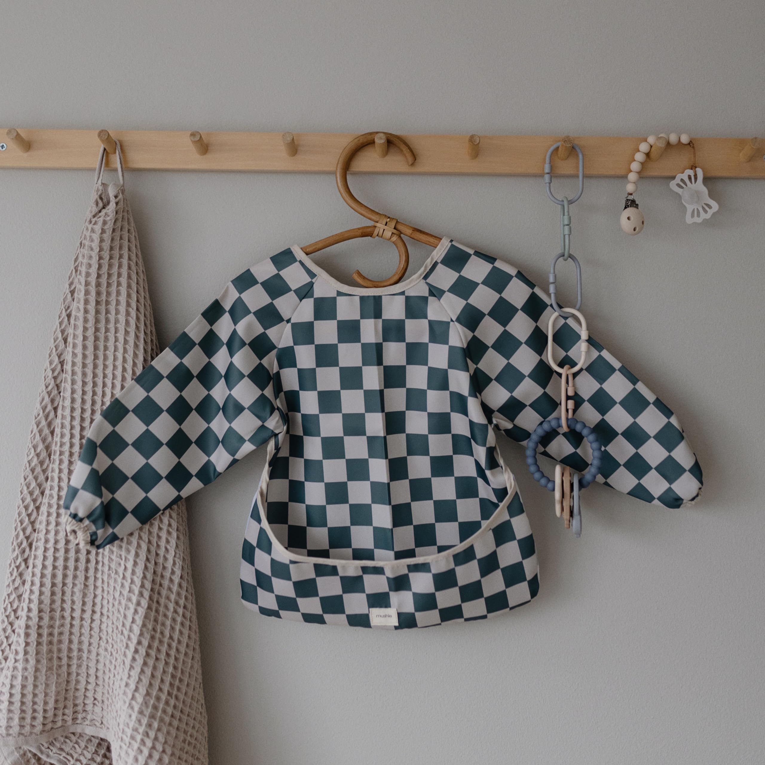 Mushie long sleeve bib olive check laid-flat drying demonstrates easy care.