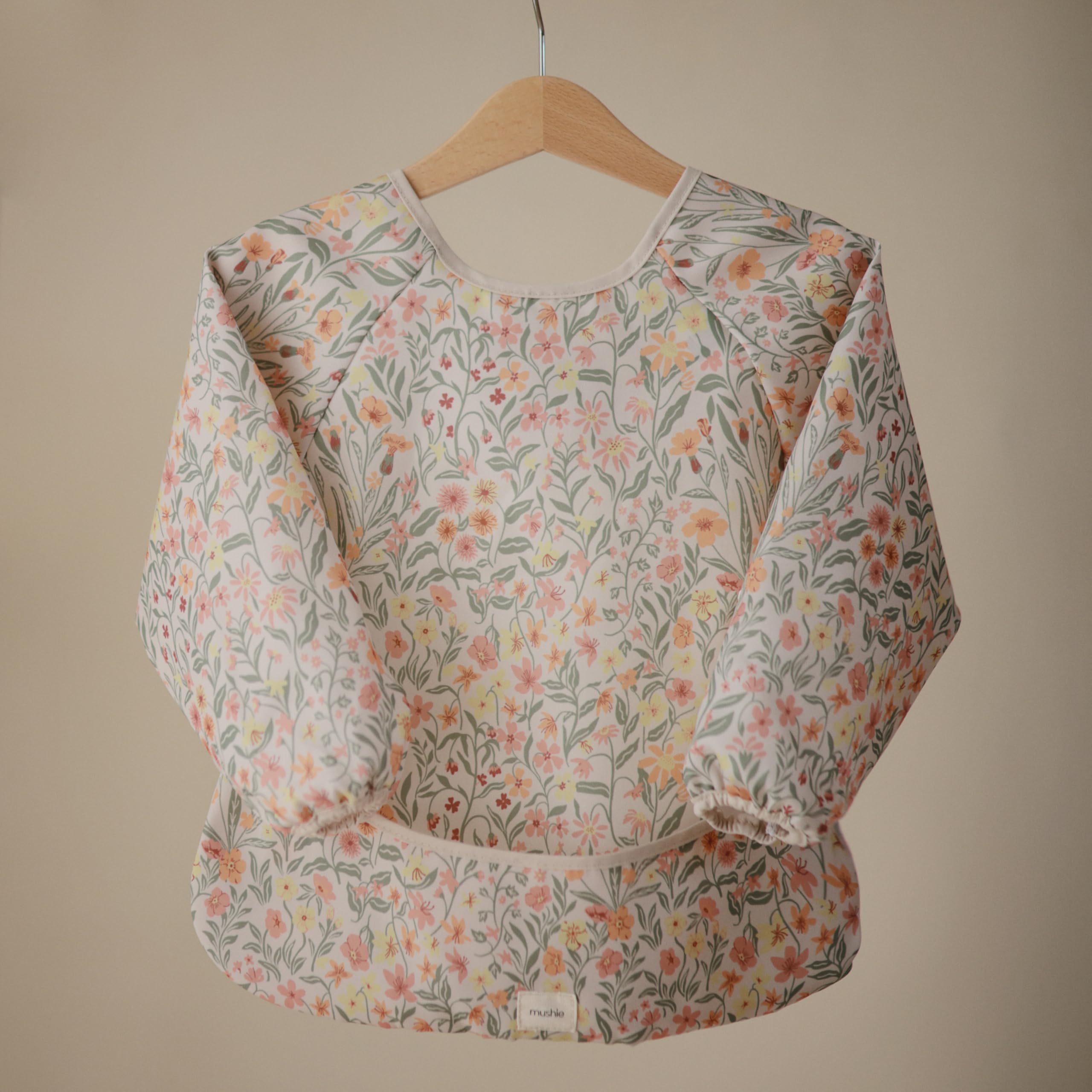 Mushie long sleeve bib water-resistant fabric demonstrates mess protection during snacks.