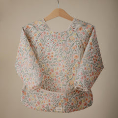 Mushie long sleeve bib water-resistant fabric demonstrates mess protection during snacks.