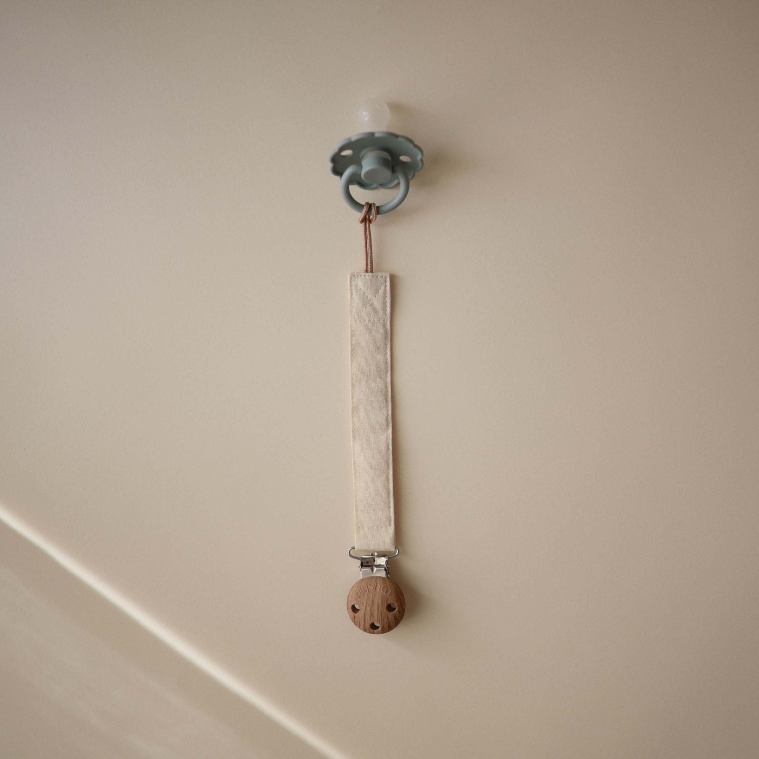 Mushie clip featuring faux wood silicone clasp for secure attachment