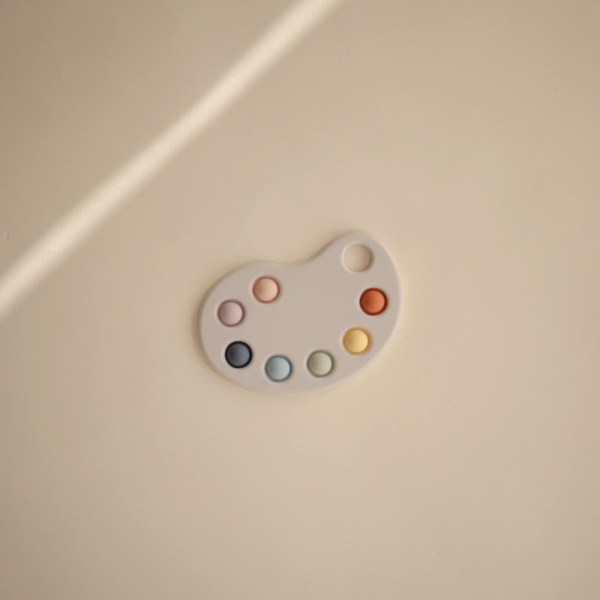 Mushie Paint Palette Press Toy soft colors emphasizing calm, engaging play.