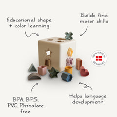Mushie Shape Sorting Box Original colorful shapes boost color recognition and language skills.