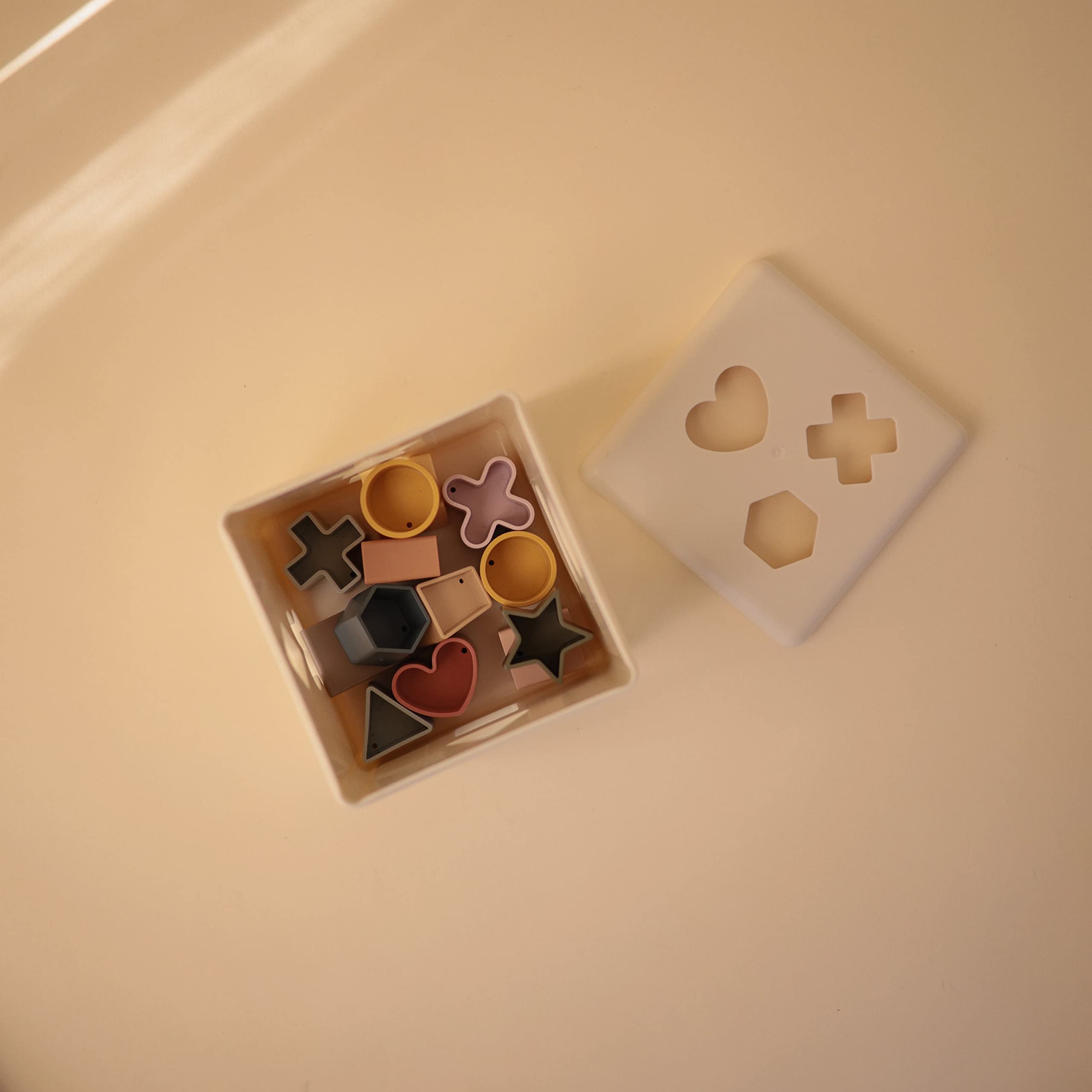 Mushie Shape Sorting Box Original with shape pieces supports early shape recognition.