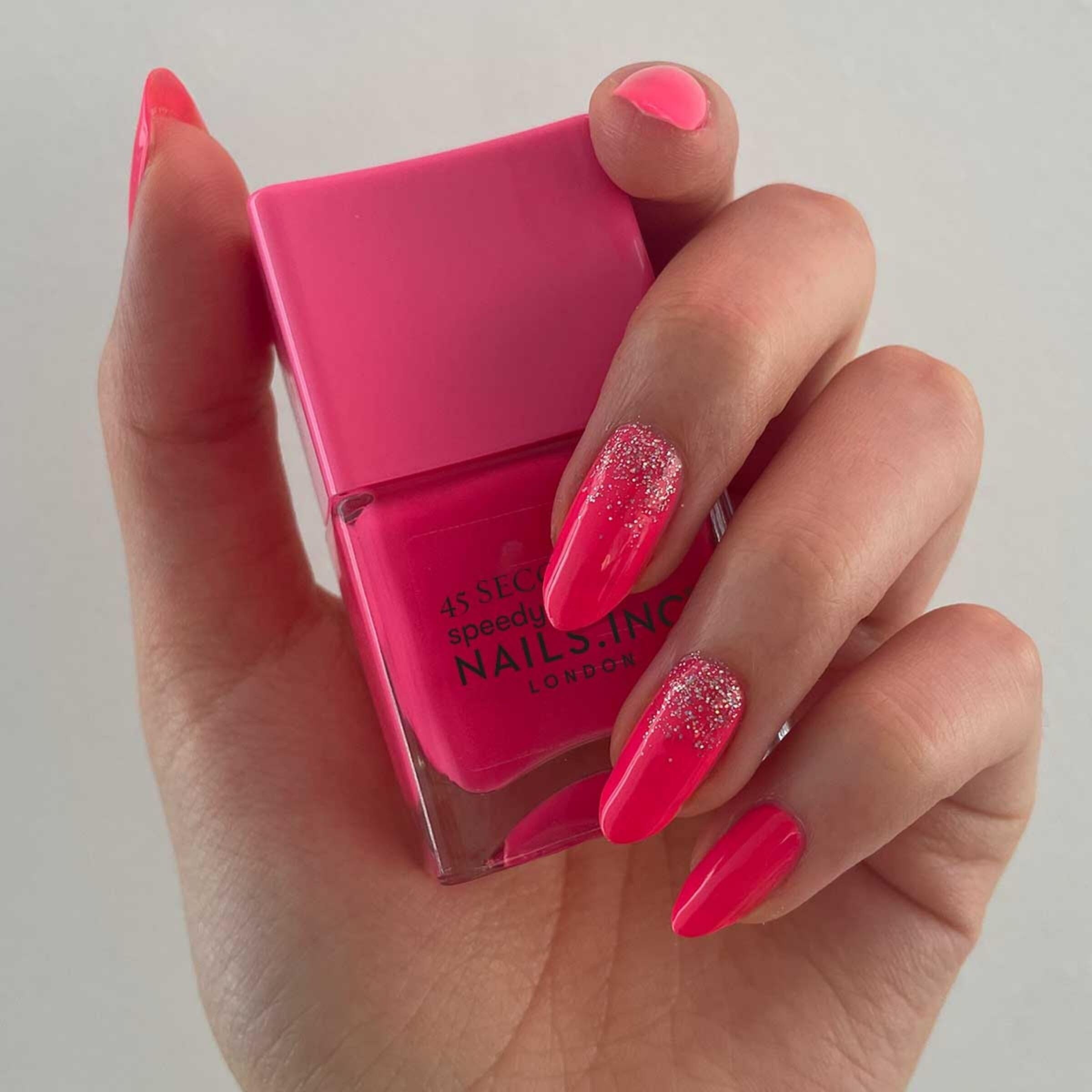 Nails INC Blake neon pink nails in use with glossy finish.