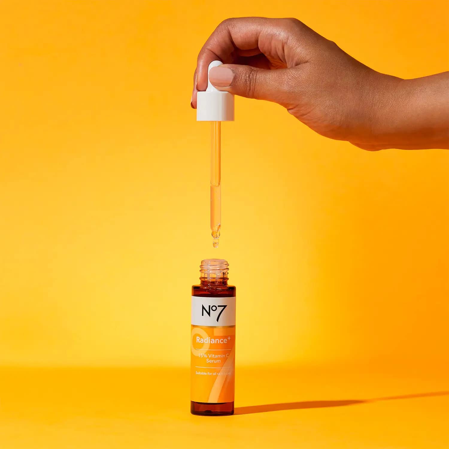 No7 Radiance+ serum bottle on a bathroom counter with soft lighting.