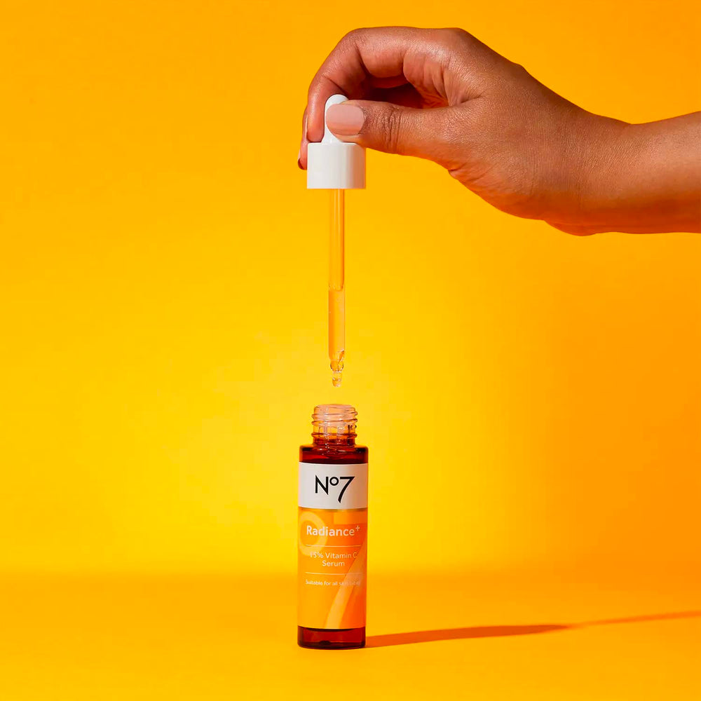 No7 Radiance+ serum bottle on a bathroom counter with soft lighting.